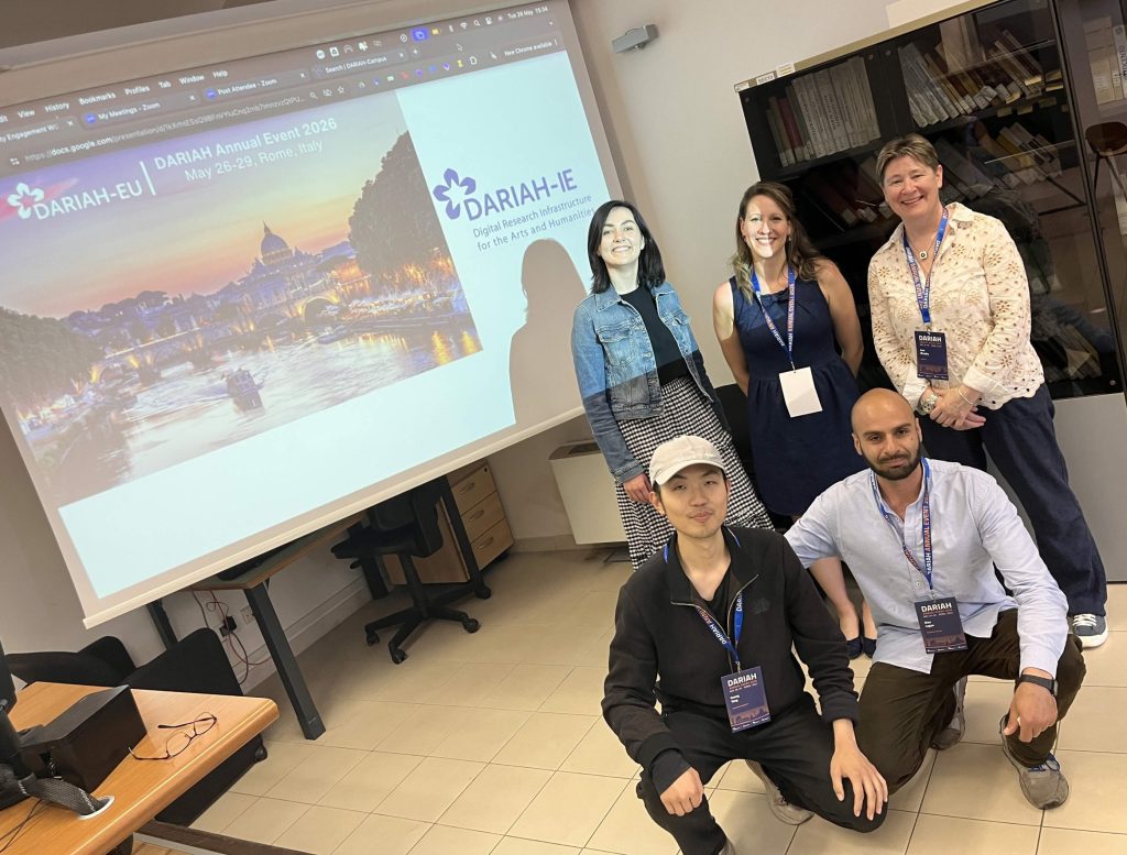 Picture of 5 people in front of screen showing DARIAH Annual Event logo